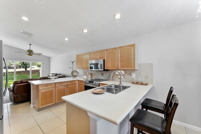 8073 Pelican Harbour Dr, Lake Worth, FL 33467 - kitchen with stainless steel appliances, a peninsula, light countertops, decorative backsplash, and light brown cabinetry