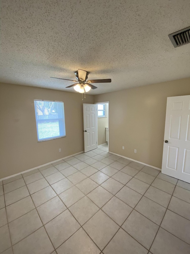 649 SW Heather St, Port Saint Lucie, FL 34983 - unfurnished room featuring ceiling fan, healthy amount of natural light, light tile patterned flooring, baseboards, and a textured ceiling