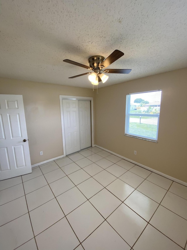 649 SW Heather St, Port Saint Lucie, FL 34983 - unfurnished bedroom with a closet, baseboards, a textured ceiling, light tile patterned floors, and ceiling fan