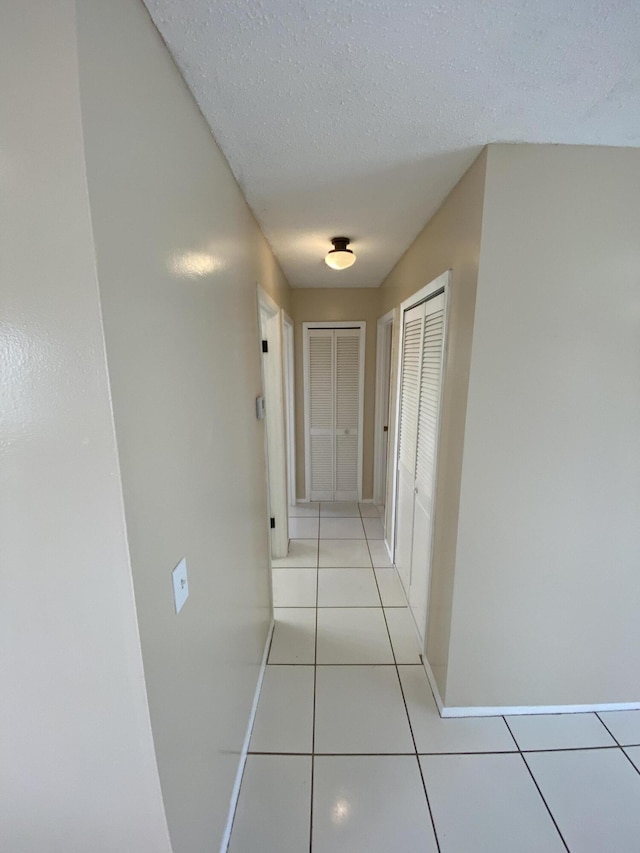 649 SW Heather St, Port Saint Lucie, FL 34983 - hallway featuring light tile patterned floors, baseboards, and a textured ceiling