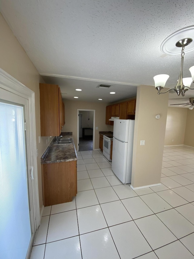 649 SW Heather St, Port Saint Lucie, FL 34983 - kitchen featuring white appliances, a sink, brown cabinets, dark countertops, and light tile patterned flooring