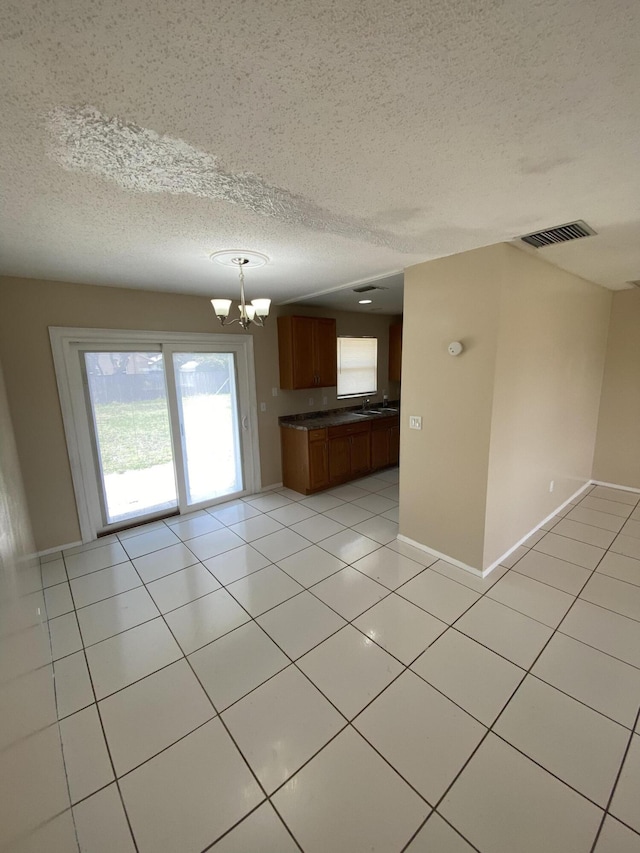 649 SW Heather St, Port Saint Lucie, FL 34983 - kitchen with dark countertops, a chandelier, a textured ceiling, open floor plan, and brown cabinets