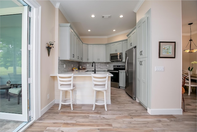 424 NE Leaping Frog Way, Port Saint Lucie, FL 34983 - kitchen featuring stainless steel appliances, ornamental molding, a peninsula, a breakfast bar, and decorative backsplash