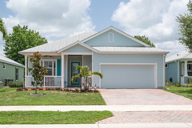 424 NE Leaping Frog Way, Port Saint Lucie, FL 34983 - view of front of property with covered porch, decorative driveway, a garage, a front yard, and a standing seam roof