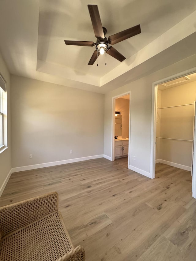 2799 Saranac Ave, West Palm Beach, FL 33409 - unfurnished bedroom featuring a raised ceiling, light wood-type flooring, a walk in closet, and ensuite bathroom