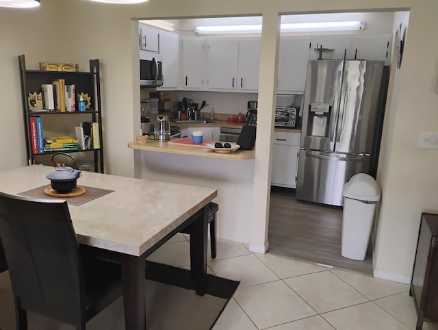 3531 Tall Pine Way Unit B-2, Greenacres, FL 33463 - kitchen with stainless steel appliances, light countertops, light tile patterned flooring, white cabinets, and a peninsula