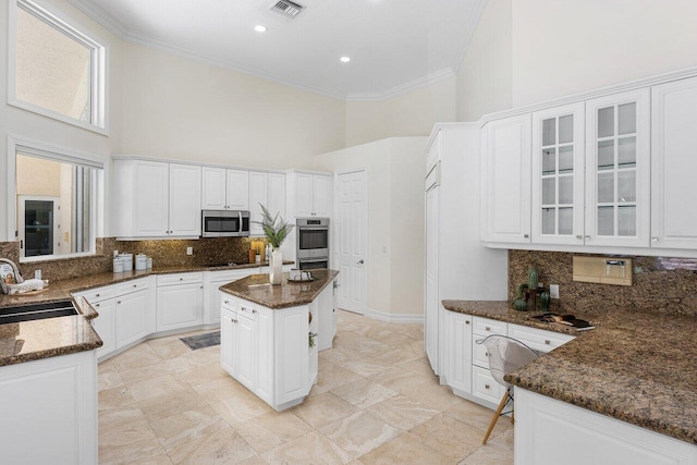 16164 Bridlewood Cir, Delray Beach, FL 33445 - kitchen featuring stainless steel microwave, a towering ceiling, a sink, crown molding, and dark stone counters