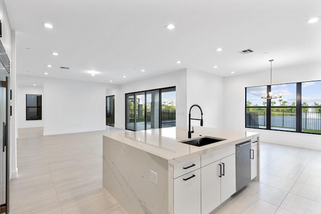 12870 Crane Xing, Palm Beach Gardens, FL 33412 - kitchen with stainless steel dishwasher, a center island with sink, decorative light fixtures, white cabinets, and light stone counters