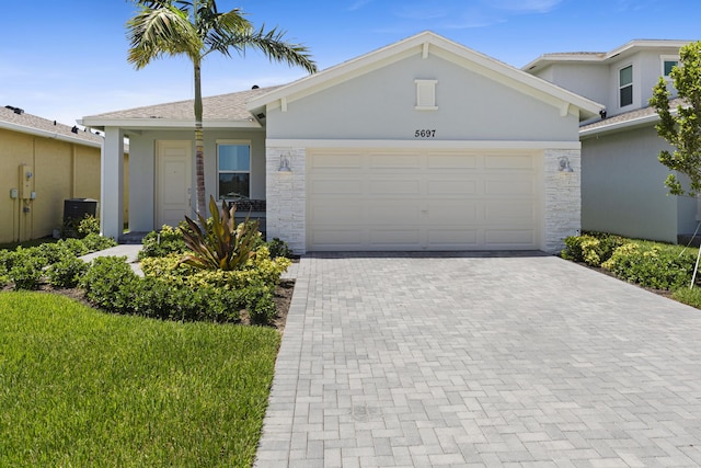 5697 Graceful Way, Delray Beach, FL 33484 - ranch-style house featuring decorative driveway, an attached garage, stucco siding, and stone siding