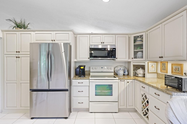 1350 SW 18th St, Boca Raton, FL 33486 - kitchen with stainless steel appliances, light stone counters, light tile patterned floors, and glass insert cabinets