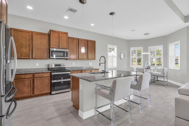 15187 Goldfinch Cir, Westlake, FL 33470 - kitchen with stainless steel appliances, brown cabinets, light wood-type flooring, dark stone countertops, and recessed lighting