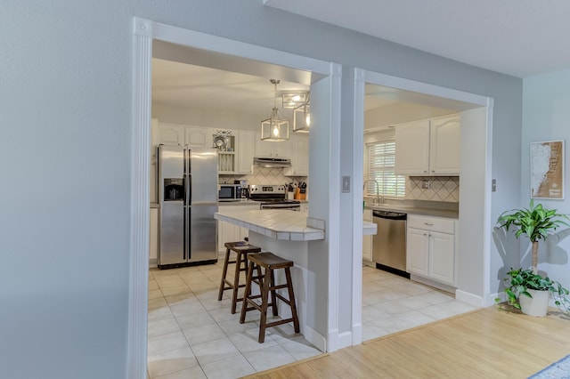 925 SW All American Blvd, Palm City, FL 34990 - kitchen featuring stainless steel appliances, a breakfast bar, under cabinet range hood, and backsplash