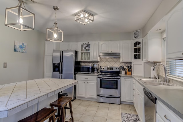 925 SW All American Blvd, Palm City, FL 34990 - kitchen with stainless steel appliances, under cabinet range hood, backsplash, light tile patterned flooring, and glass insert cabinets