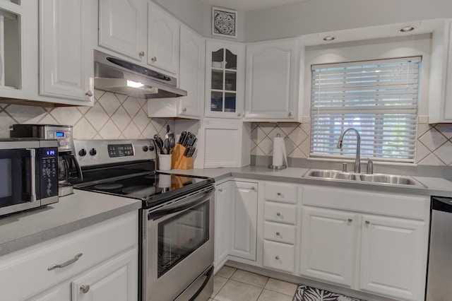 925 SW All American Blvd, Palm City, FL 34990 - kitchen with appliances with stainless steel finishes, under cabinet range hood, white cabinets, glass insert cabinets, and decorative backsplash