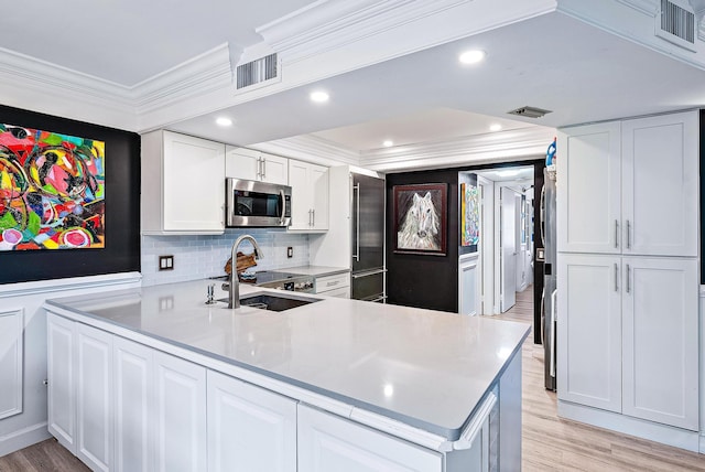 1605 S US Highway 1 Unit F202, Jupiter, FL 33477 - kitchen with stainless steel microwave, crown molding, light countertops, light wood-style flooring, and white cabinetry