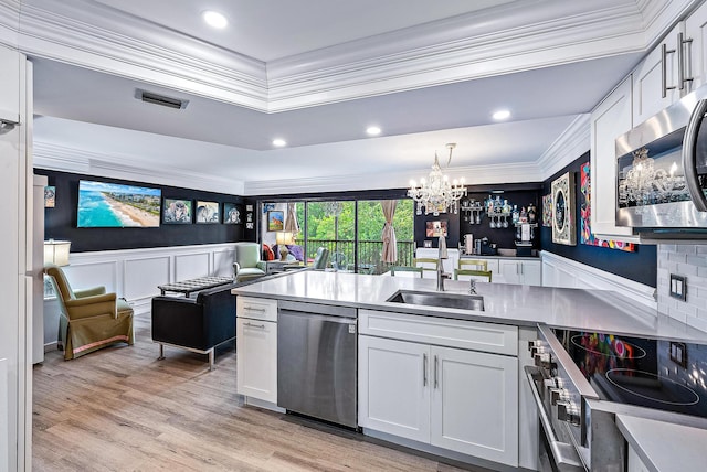 1605 S US Highway 1 Unit F202, Jupiter, FL 33477 - kitchen featuring stainless steel appliances, crown molding, a chandelier, white cabinetry, and light wood-type flooring
