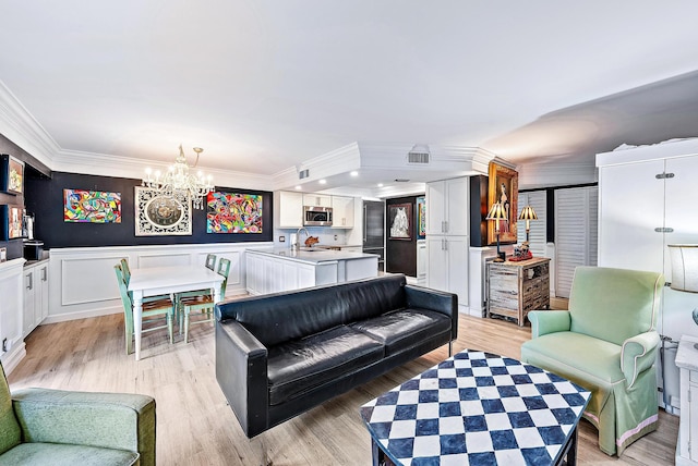 1605 S US Highway 1 Unit F202, Jupiter, FL 33477 - living room featuring crown molding, a chandelier, a wainscoted wall, and light wood-style floors