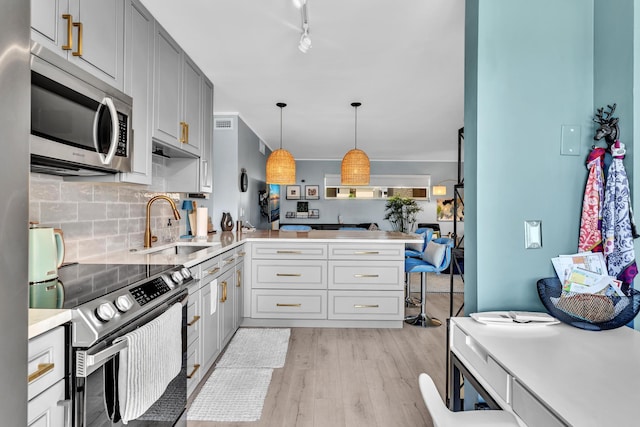 2 Colonial Club Dr Unit 203, Boynton Beach, FL 33435 - kitchen featuring appliances with stainless steel finishes, a peninsula, light countertops, light wood-style floors, and tasteful backsplash