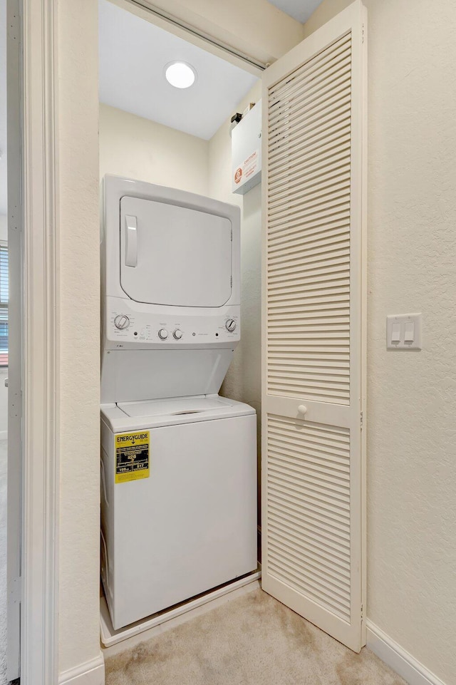 770 Millbrae 4 Ct Unit 4, West Palm Beach, FL 33401 - laundry area with stacked washer and clothes dryer, light colored carpet, and a textured wall