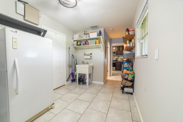1450 SW 28th St, Okeechobee, FL 34974 - kitchen featuring freestanding refrigerator, a textured ceiling, light tile patterned floors, and open shelves