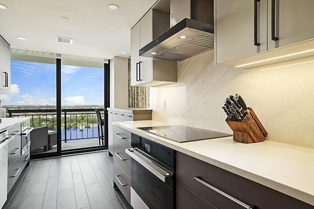 2001 N Ocean Blvd Unit 1804, Boca Raton, FL 33431 - kitchen with oven, wall chimney range hood, modern cabinets, a wall of windows, and light countertops