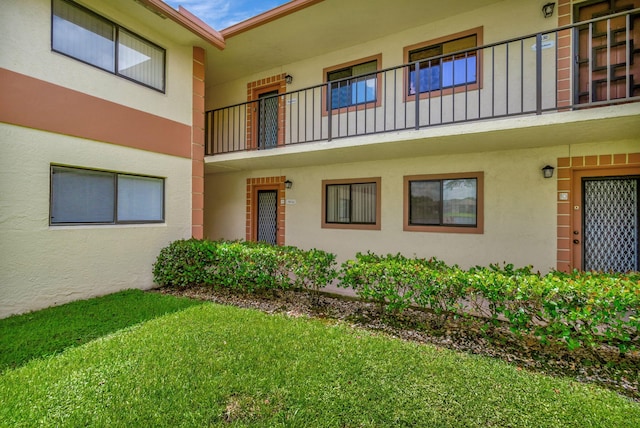 15401 Pembridge Ave Unit 9, Delray Beach, FL 33484 - view of front of house with stucco siding, a balcony, and a front lawn