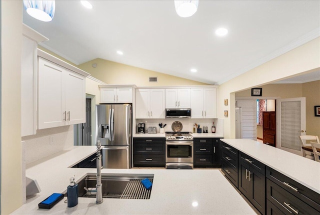 2990 SW Ventura St, Port Saint Lucie, FL 34953 - kitchen with stainless steel appliances, dark cabinets, white cabinets, light countertops, and vaulted ceiling