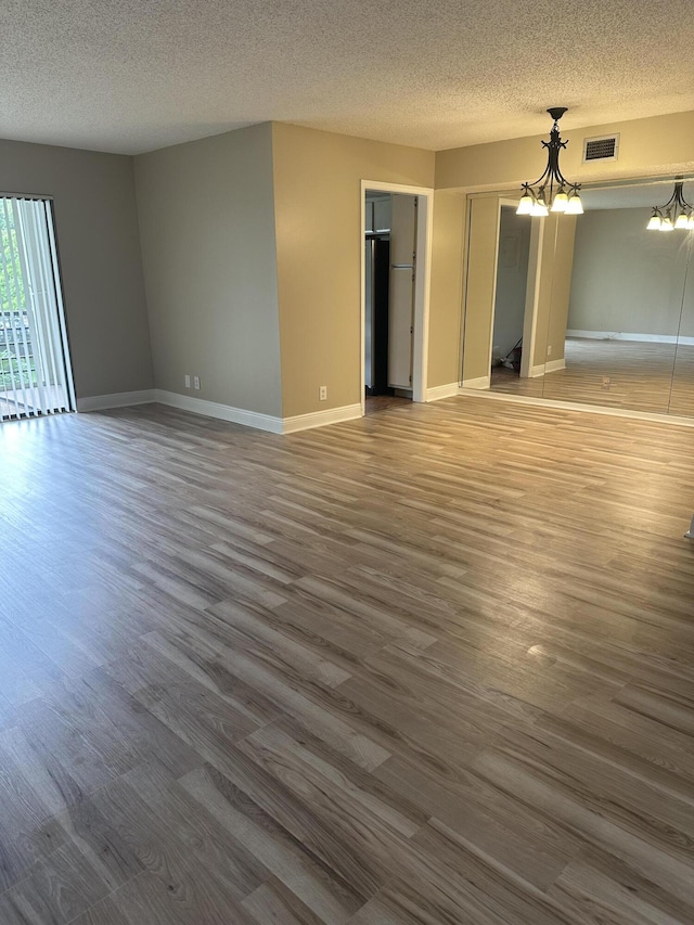 5917 Via Vermilya Unit 306, Lake Worth, FL 33462 - unfurnished living room with wood finished floors, a textured ceiling, and a chandelier