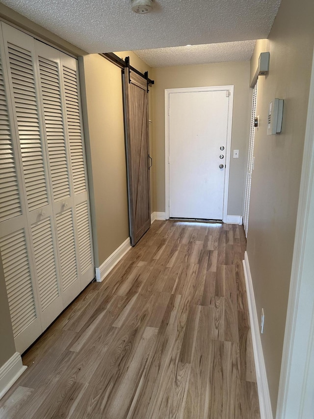 5917 Via Vermilya Unit 306, Lake Worth, FL 33462 - hallway with a barn door, light wood-style flooring, and a textured ceiling