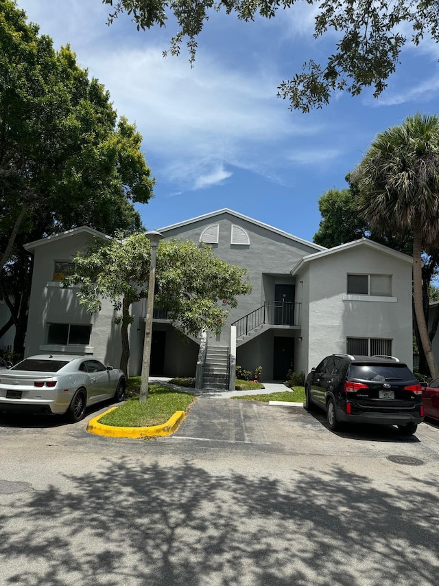 984 Lake Victoria Dr Unit B, West Palm Beach, FL 33411 - view of front of house featuring stairway, stucco siding, and uncovered parking