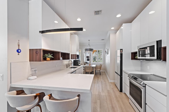 231 Caravelle Dr, Jupiter, FL 33458 - kitchen featuring stainless steel appliances, modern cabinets, recessed lighting, white cabinets, and light wood finished floors