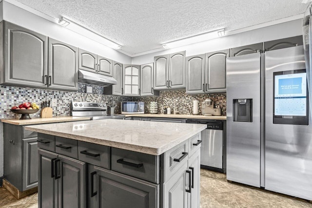 22180 Boca Rancho Dr Unit B, Boca Raton, FL 33428 - kitchen featuring appliances with stainless steel finishes, under cabinet range hood, a textured ceiling, a center island, and backsplash