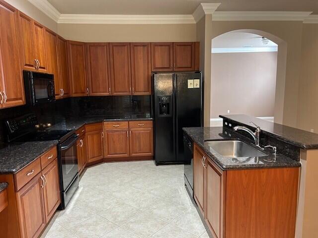 9916 E Tallyrand Dr, Lake Worth, FL 33467 - kitchen with black appliances, arched walkways, crown molding, a center island with sink, and brown cabinetry