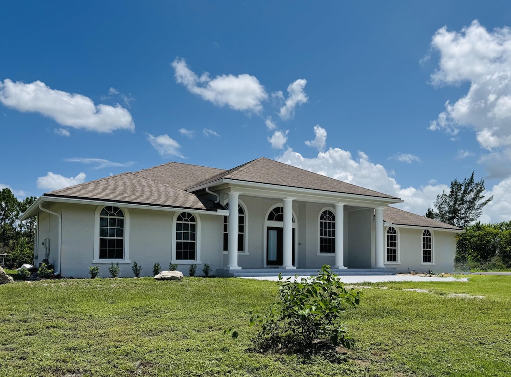 17978 83rd Pl N, The Acreage, FL 33470 - view of front of home with stucco siding, a front lawn, covered porch, and a shingled roof