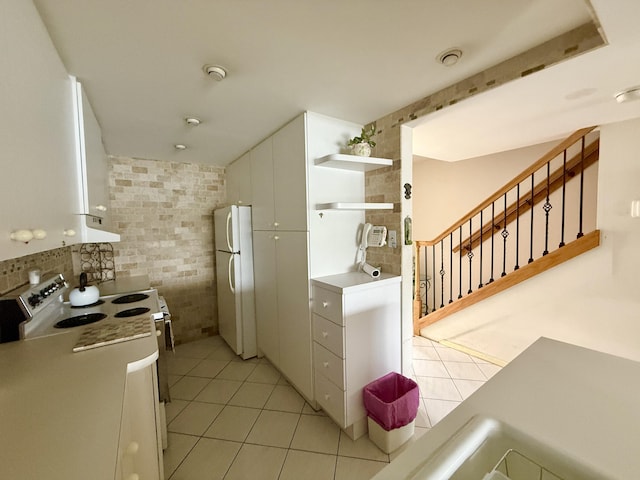 1100 Crystal Lake Dr Unit 107, Deerfield Beach, FL 33064 - kitchen featuring white appliances, light tile patterned flooring, open shelves, white cabinets, and tile walls