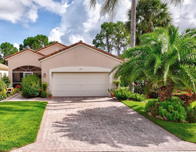 352 NW Granville St, Port Saint Lucie, FL 34986 - mediterranean / spanish-style house featuring stucco siding, an attached garage, decorative driveway, a front yard, and a tiled roof
