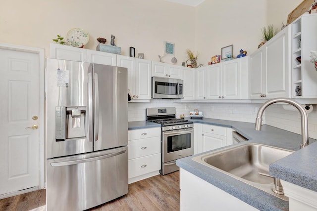 352 NW Granville St, Port Saint Lucie, FL 34986 - kitchen featuring appliances with stainless steel finishes, white cabinetry, decorative backsplash, and light wood-type flooring