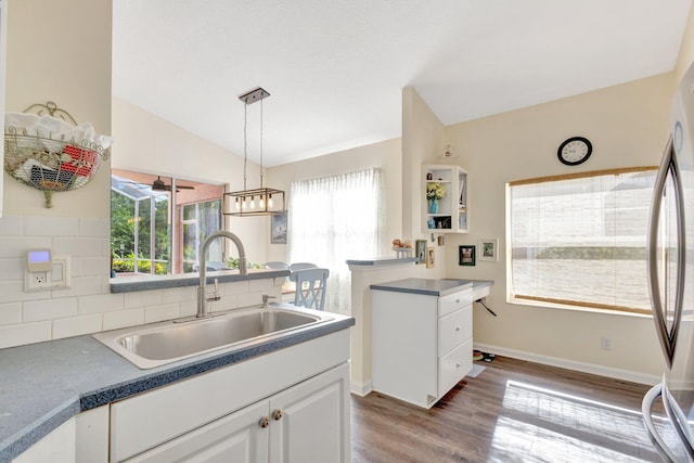 352 NW Granville St, Port Saint Lucie, FL 34986 - kitchen featuring plenty of natural light, wood finished floors, vaulted ceiling, white cabinets, and decorative light fixtures