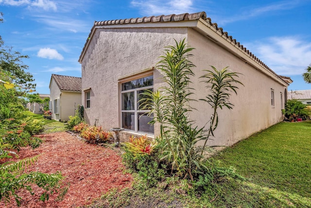 352 NW Granville St, Port Saint Lucie, FL 34986 - view of home's exterior featuring stucco siding, a tile roof, and a lawn