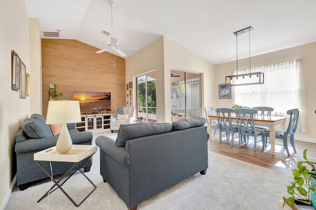 352 NW Granville St, Port Saint Lucie, FL 34986 - living area featuring lofted ceiling, a ceiling fan, wood walls, light wood finished floors, and light carpet
