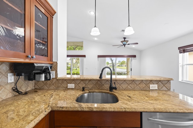 7117 Treviso Ln, Boynton Beach, FL 33472 - kitchen with stainless steel dishwasher, vaulted ceiling, tasteful backsplash, brown cabinets, and light stone countertops