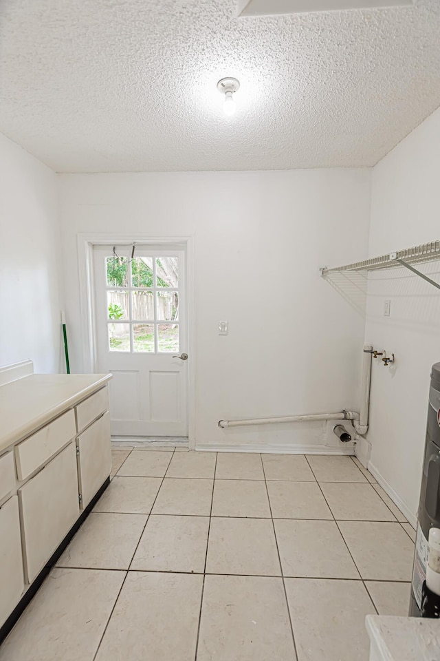 706 Azalea Ave, Fort Pierce, FL 34982 - laundry room with cabinet space, light tile patterned floors, a textured ceiling, and water heater