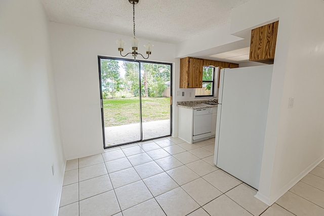 706 Azalea Ave, Fort Pierce, FL 34982 - kitchen featuring white appliances, a chandelier, brown cabinets, light tile patterned flooring, and a textured ceiling