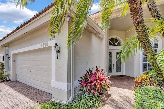 6496 San Michel Way, Delray Beach, FL 33484 - doorway to property with french doors, stucco siding, a garage, a tiled roof, and driveway