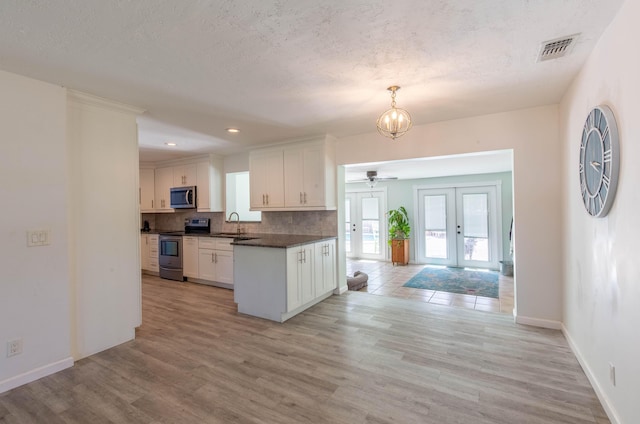 12069 Easterly Ave, Palm Beach Gardens, FL 33410 - kitchen featuring stainless steel appliances, french doors, dark countertops, light wood-style flooring, and white cabinetry