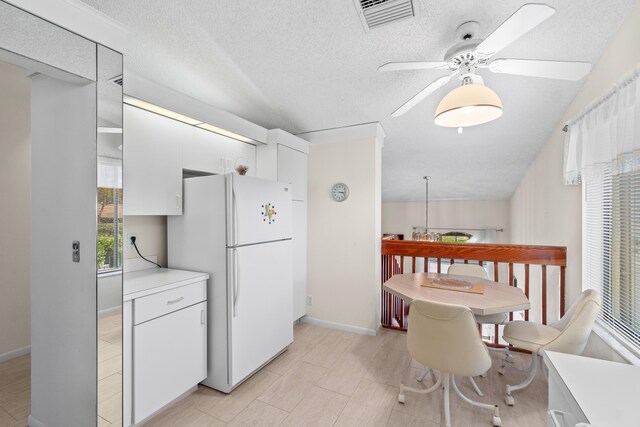 10263 N Circle Lake Dr Unit 201, Boynton Beach, FL 33437 - kitchen with freestanding refrigerator, ceiling fan, light countertops, white cabinetry, and a textured ceiling