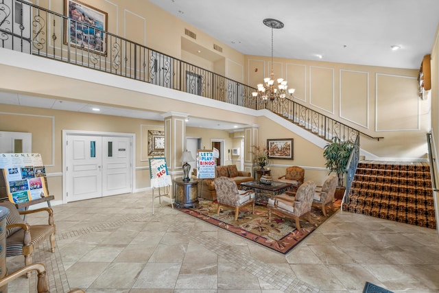 10263 N Circle Lake Dr Unit 201, Boynton Beach, FL 33437 - living area with stairway, decorative columns, a towering ceiling, a chandelier, and tile patterned flooring