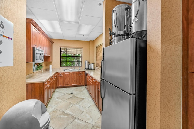 10263 N Circle Lake Dr Unit 201, Boynton Beach, FL 33437 - kitchen featuring stainless steel appliances, light countertops, brown cabinets, wallpapered walls, and a drop ceiling