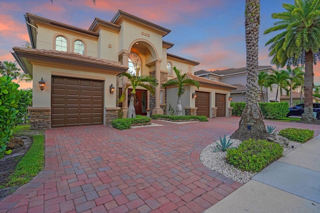718 Edgebrook Ln, West Palm Beach, FL 33411 - mediterranean / spanish-style home featuring decorative driveway, stucco siding, stone siding, and an attached garage