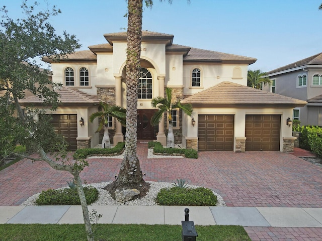 718 Edgebrook Ln, West Palm Beach, FL 33411 - mediterranean / spanish house with a garage, stucco siding, decorative driveway, and stone siding